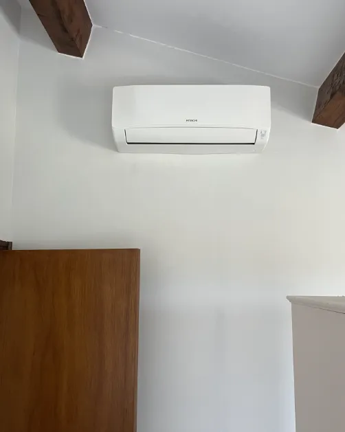 Unité murale Hitachi installée dans une pièce avec des poutres en bois