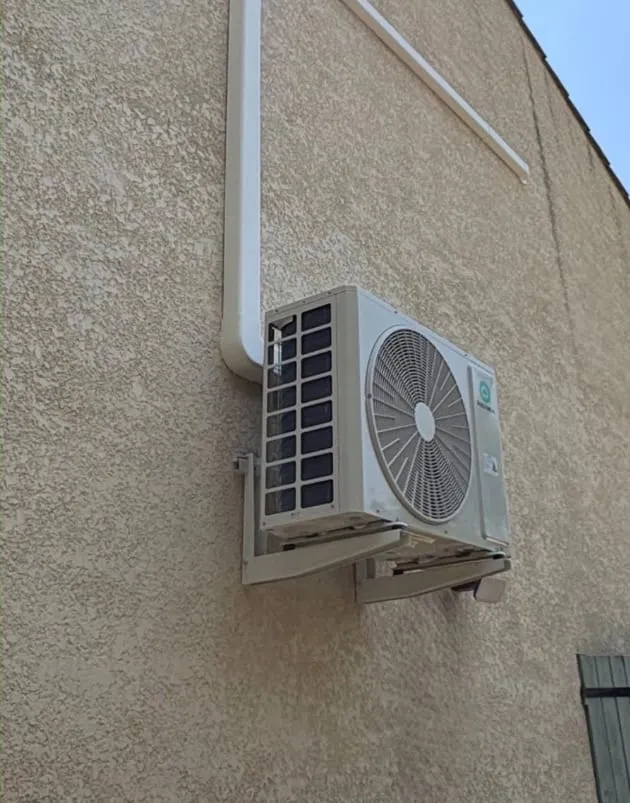 Unité extérieure de climatisation fixée sur une façade crépie