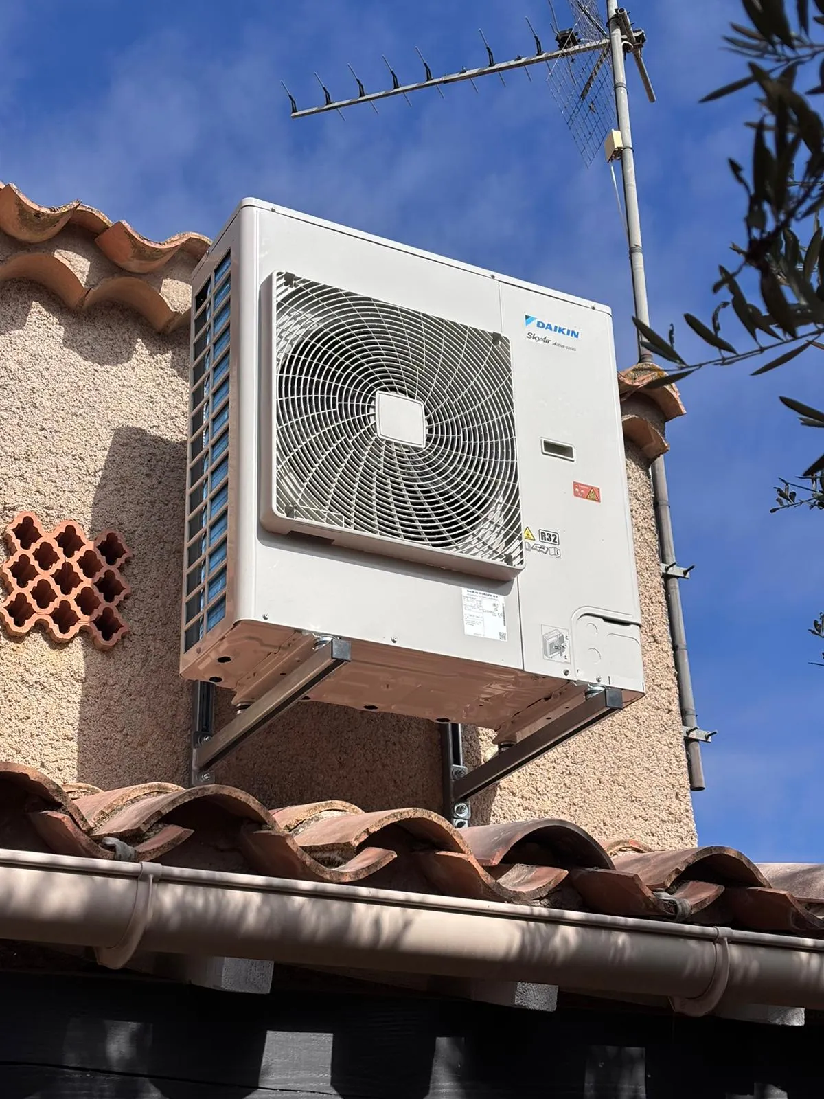 Unité extérieure Daikin SkyAir fixée sur des supports métalliques contre une façade crépie