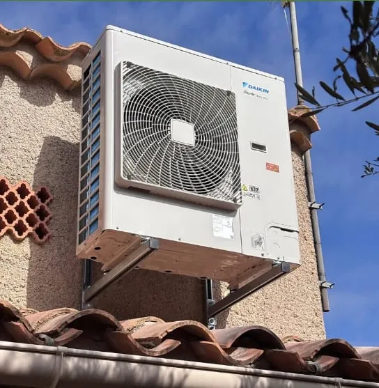 Unité extérieure Daikin fixée sur des supports métalliques contre une façade crépie, sous un ciel bleu