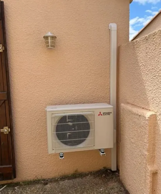 Unité extérieure Mitsubishi Electric fixée sur la façade d’une maison.
