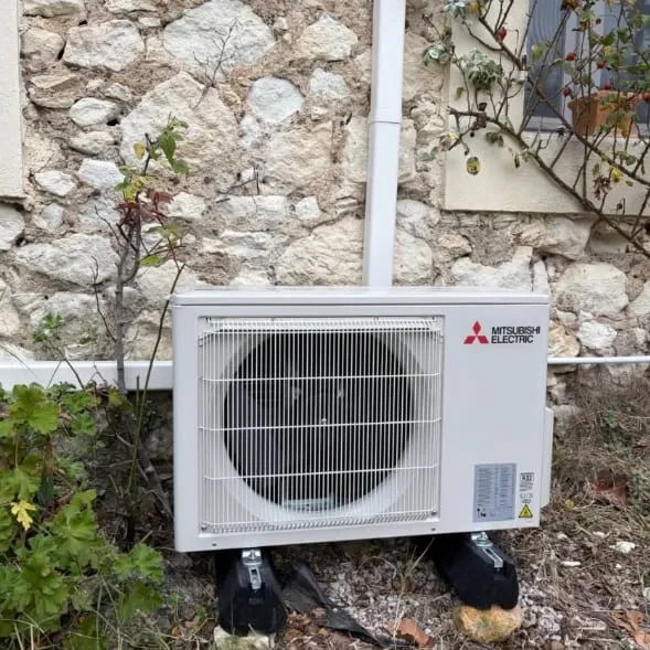 Unité extérieure Mitsubishi Electric installée devant un mur en pierre