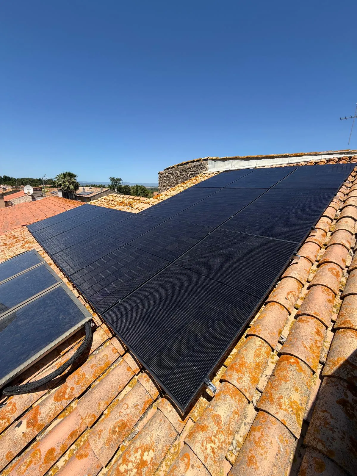 Panneaux photovoltaïques noirs sur une toiture en tuiles canal sous un ciel bleu