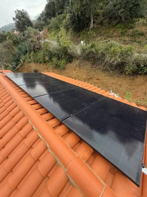 Panneaux photovoltaïques noirs installés sur une toiture en tuiles terre cuite