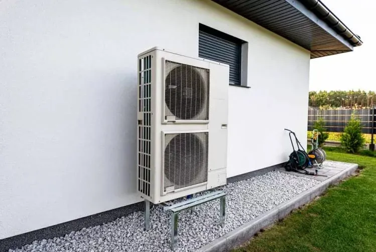 Unité extérieure de pompe à chaleur installée contre le mur blanc d’une maison